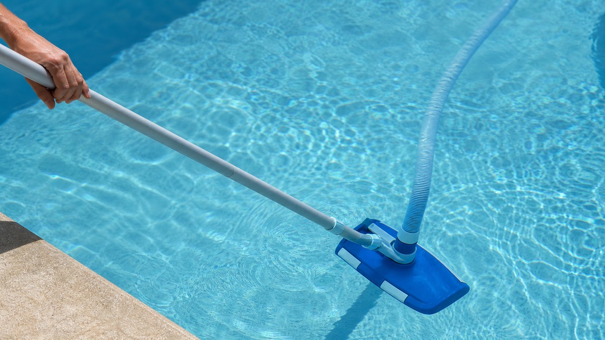 Pulitore manuale con testina e asta che aspira il fondo di una piscina residenziale